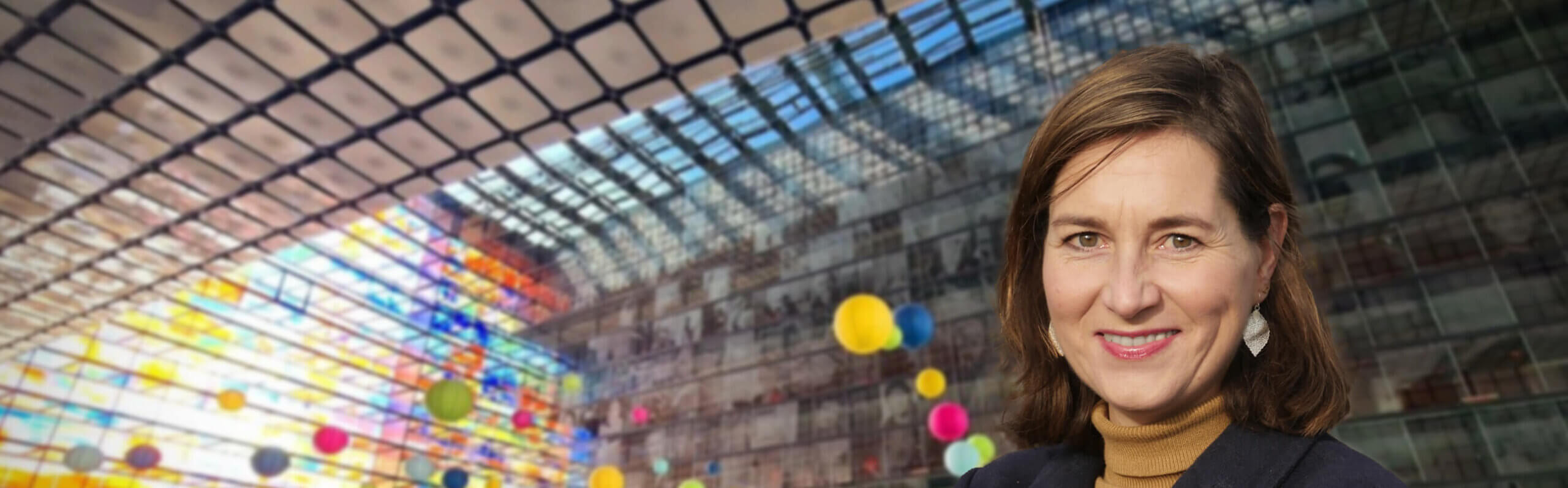 Lachende Ulrike Nagel met bruin haar voor het kleurrijke glazen dak van het museum Beeld en Geluid in Hilversum